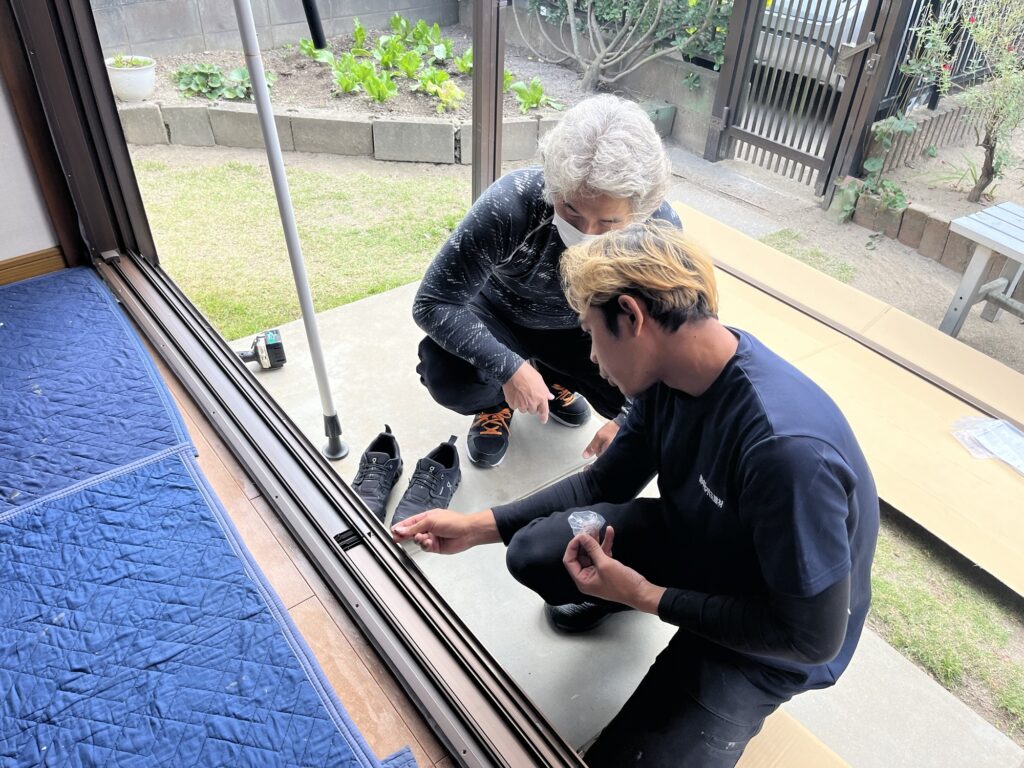 窓の工事を職人が技能実習生に教えているところ