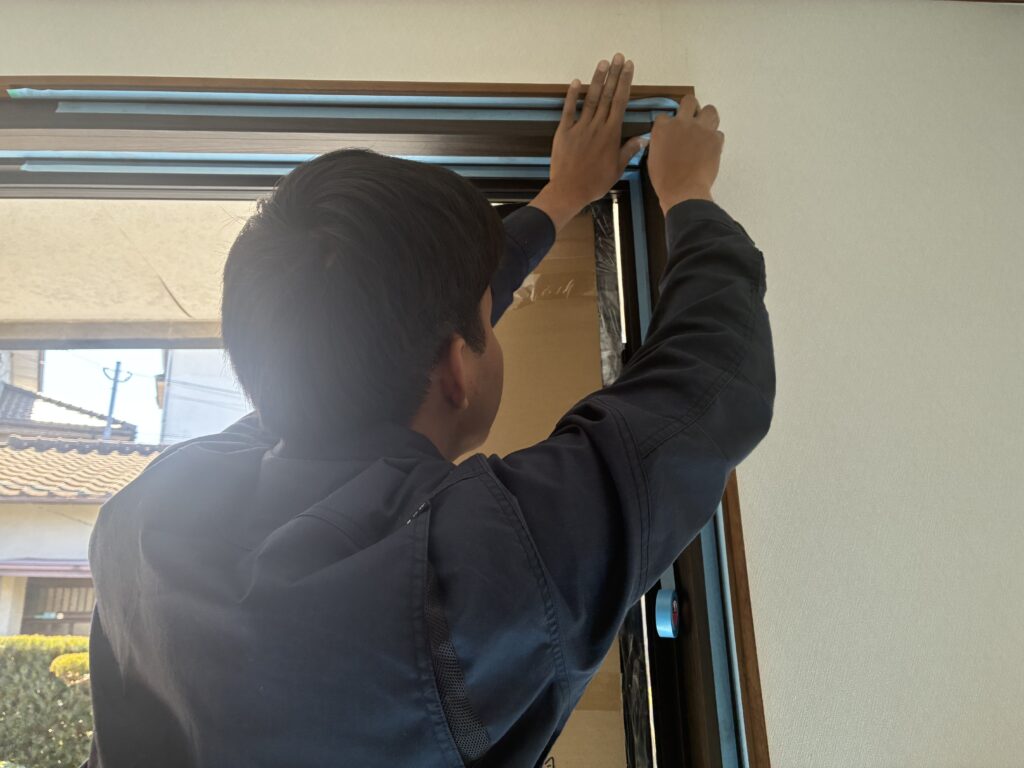 南区桧原ドアリフォーム中の
コーキング作業前のマスキングテープを貼っている様子