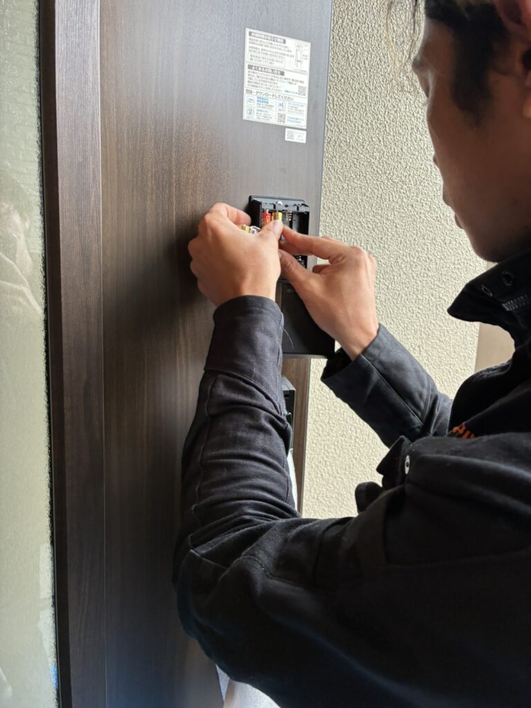玄関ドアへ電池を入れる様子
