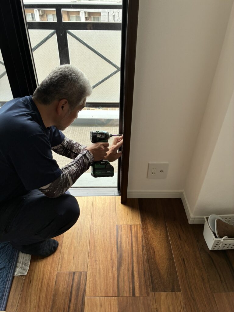 窓の右側に枠にネジを打ち込む様子